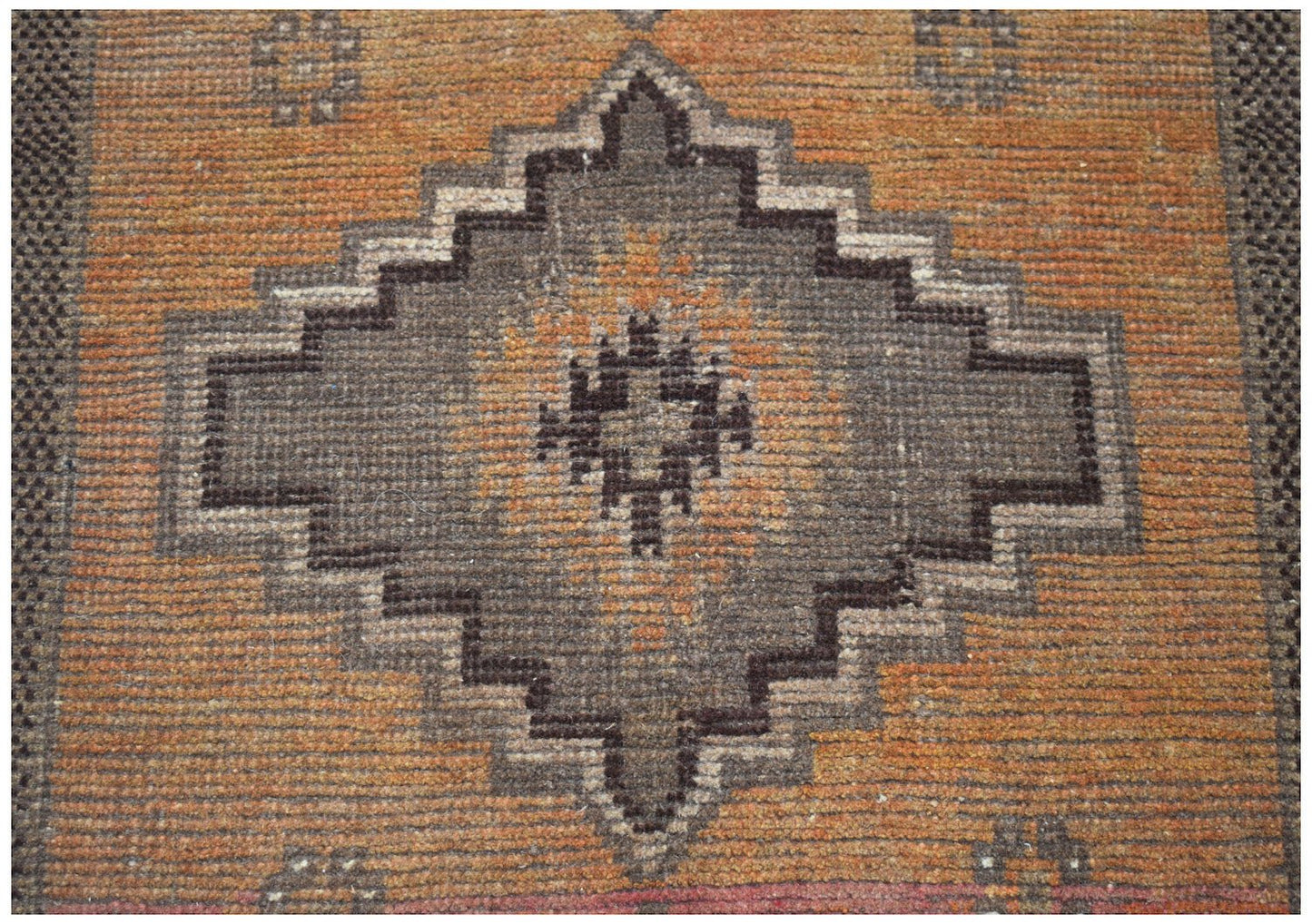 Handmade Afghan Baluch rug featuring a geometric diamond medallion in brown on an orange field.
