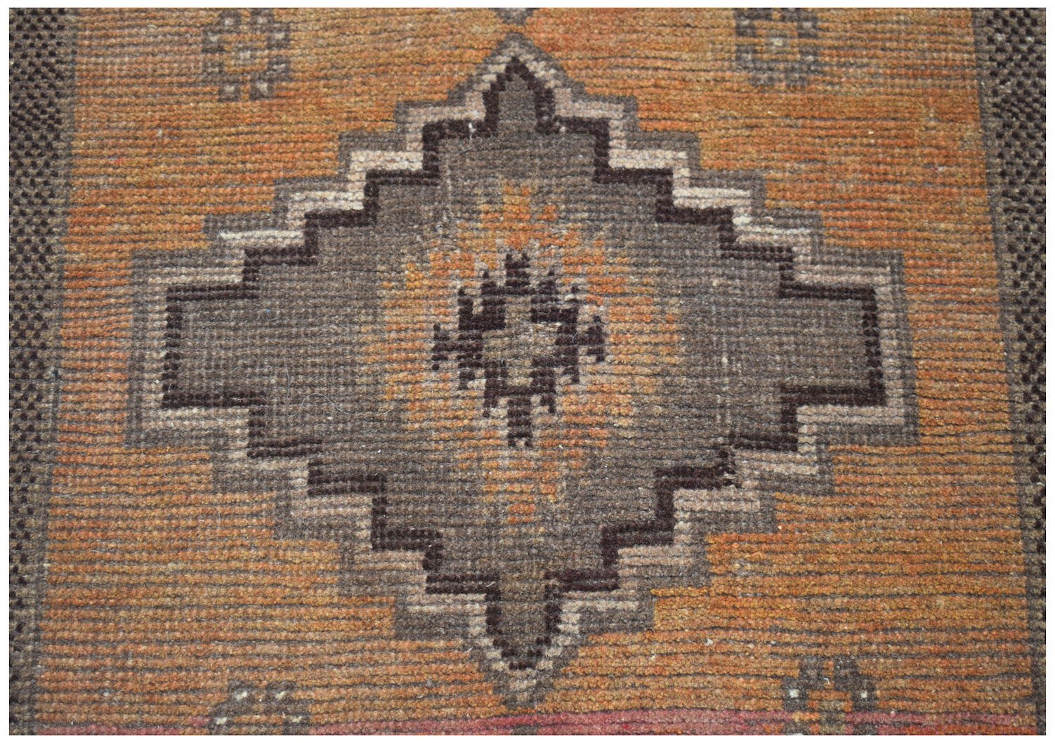 Handmade Afghan Baluch rug featuring a geometric diamond medallion in brown on an orange field.