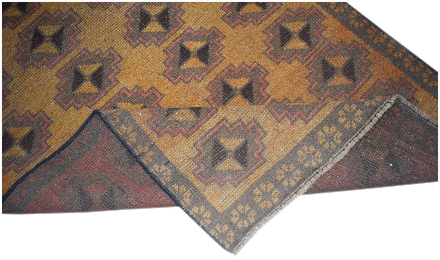 A handmade Afghan Baluch rug featuring a geometric pattern in shades of gold, brown, and red.