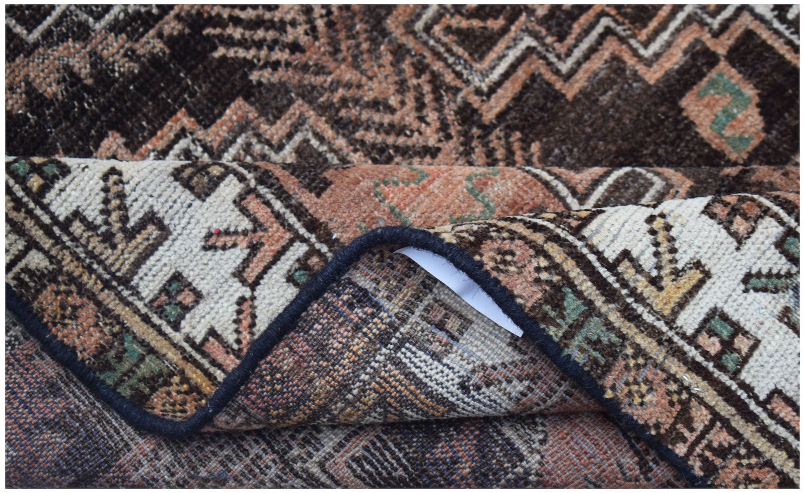 A close-up view of a handmade Afghan Baluch rug showing its intricate geometric pattern and weave.