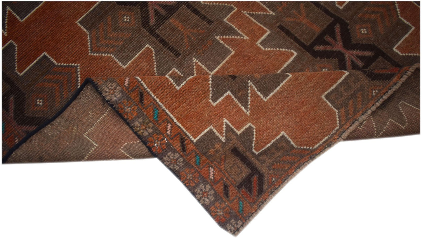 A handmade Afghan Baluch rug featuring geometric patterns in shades of brown and burnt orange.