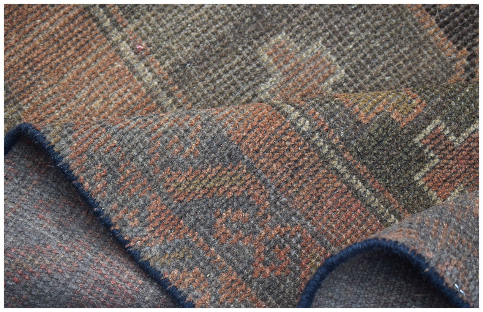 A close-up view of a handmade Afghan Baluch rug featuring a geometric pattern in brown and rust.
