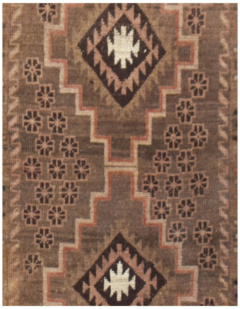 Handmade Afghan Baluch rug featuring a brown field with geometric diamond motifs and floral accents.