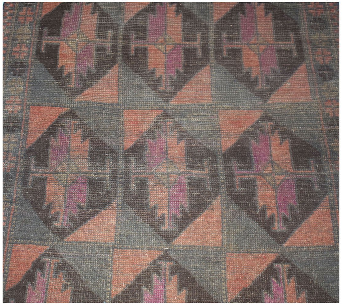 Handmade Afghan Baluch rug featuring a repeating geometric diamond pattern in dark wool tones.