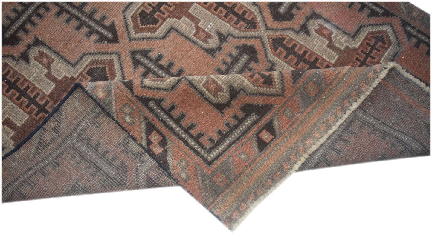 A handmade Afghan Baluch rug featuring geometric patterns in shades of brown and terracotta.