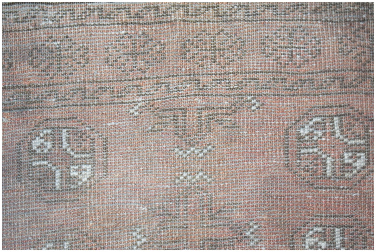 A handmade Afghan Baluch rug featuring geometric patterns in shades of red and brown.
