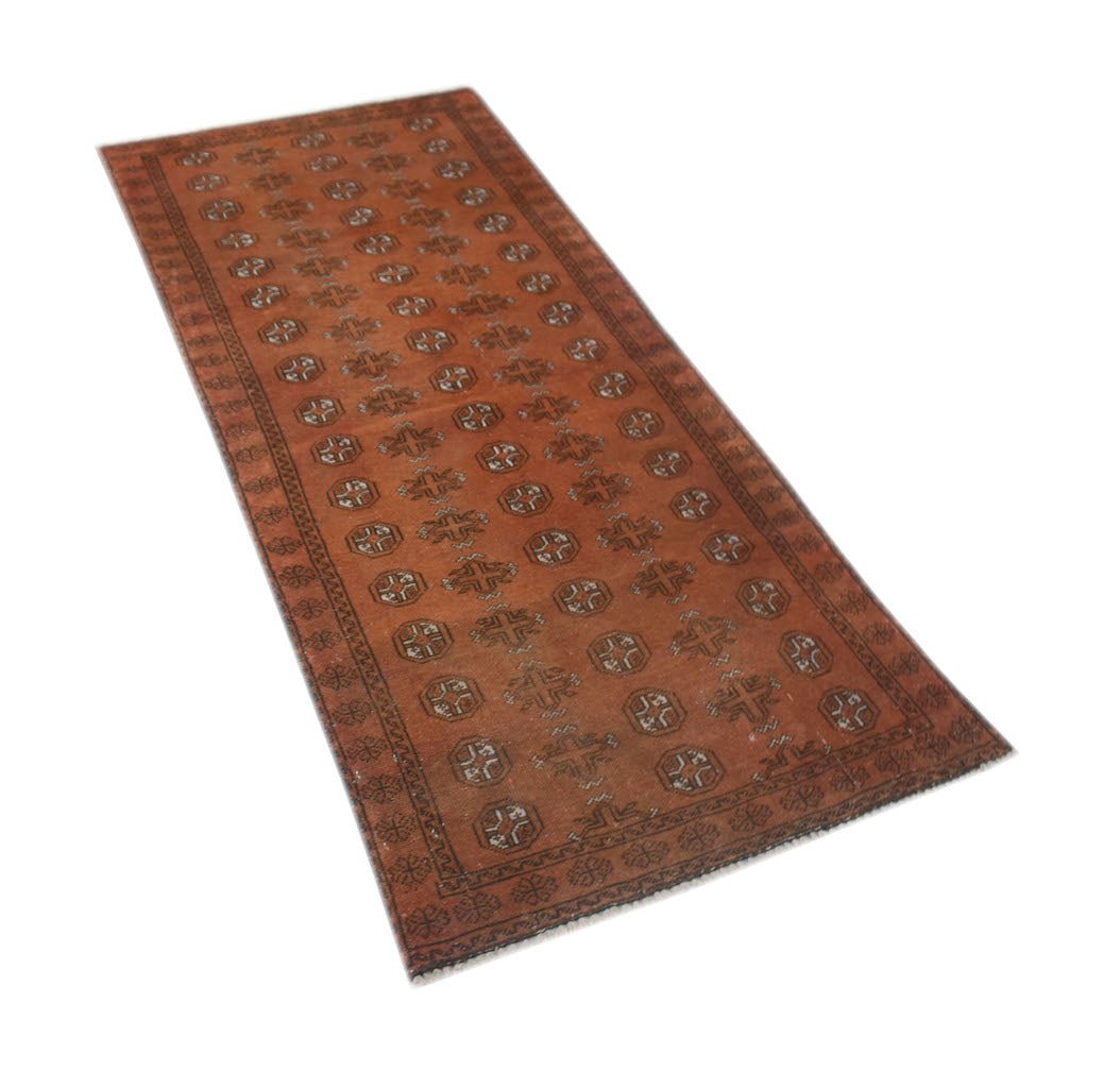 A handmade Afghan Baluch runner rug featuring a repeating geometric pattern in shades of rust red.
