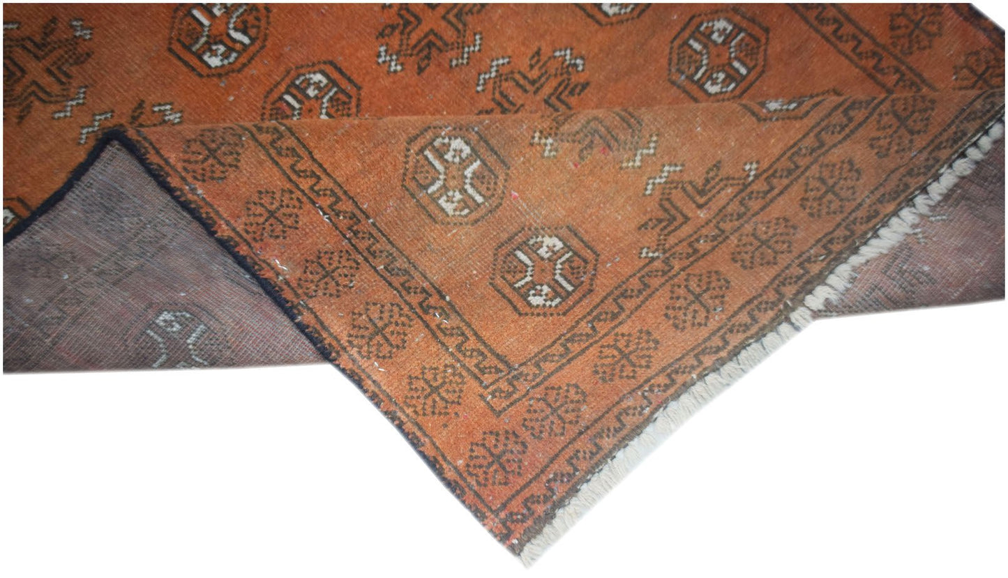 Handmade Afghan Baluch rug featuring a geometric pattern in shades of orange and dark brown.