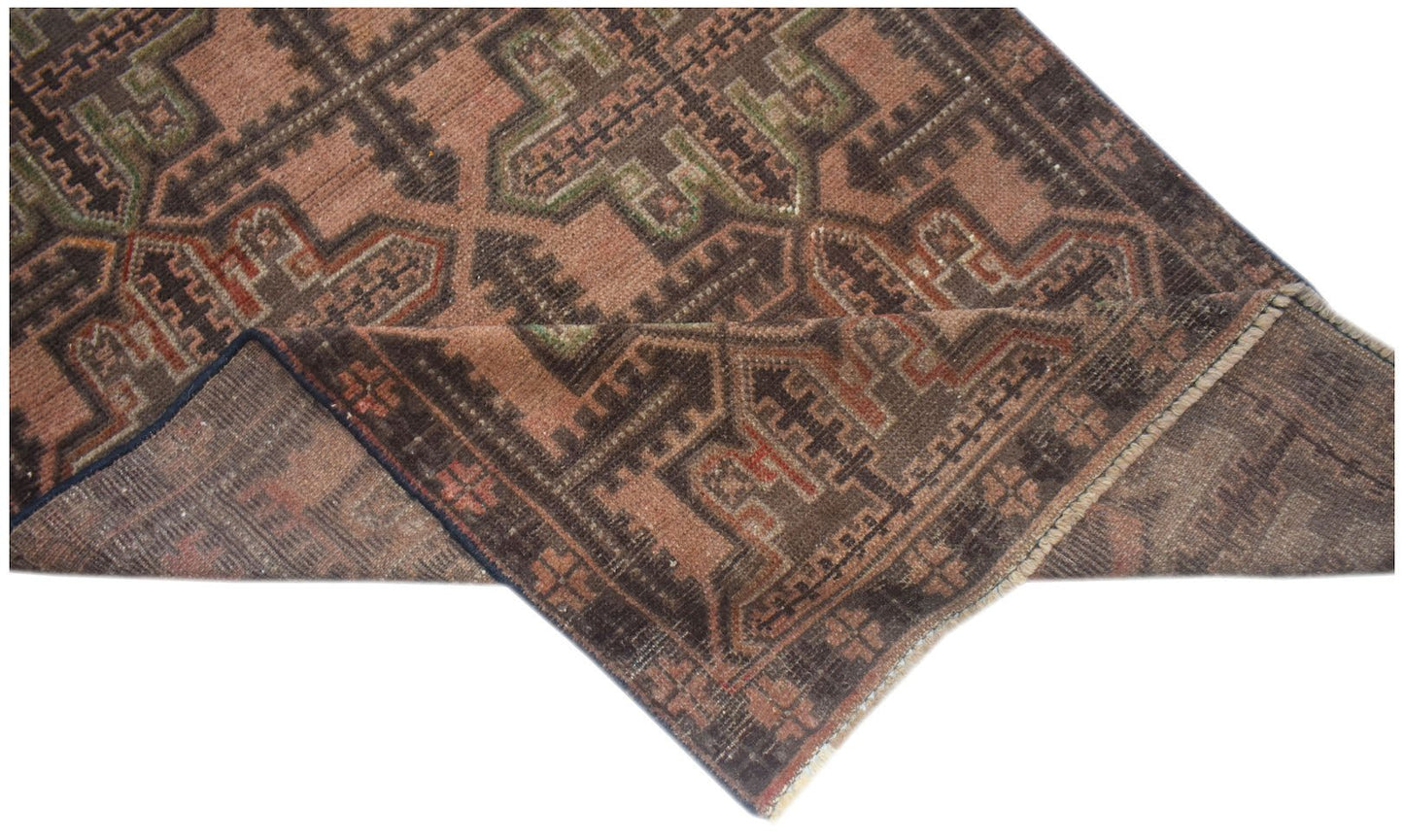 A handmade Afghan Baluch rug featuring a geometric pattern in shades of brown, rust, and green.