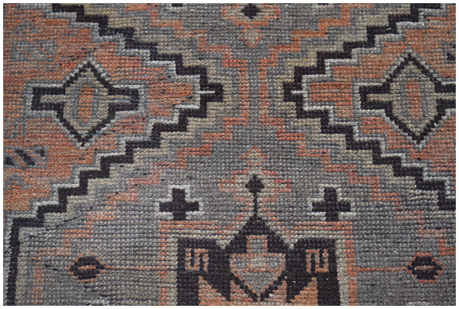 Handmade Afghan Baluch rug featuring a geometric pattern in shades of grey and terracotta.