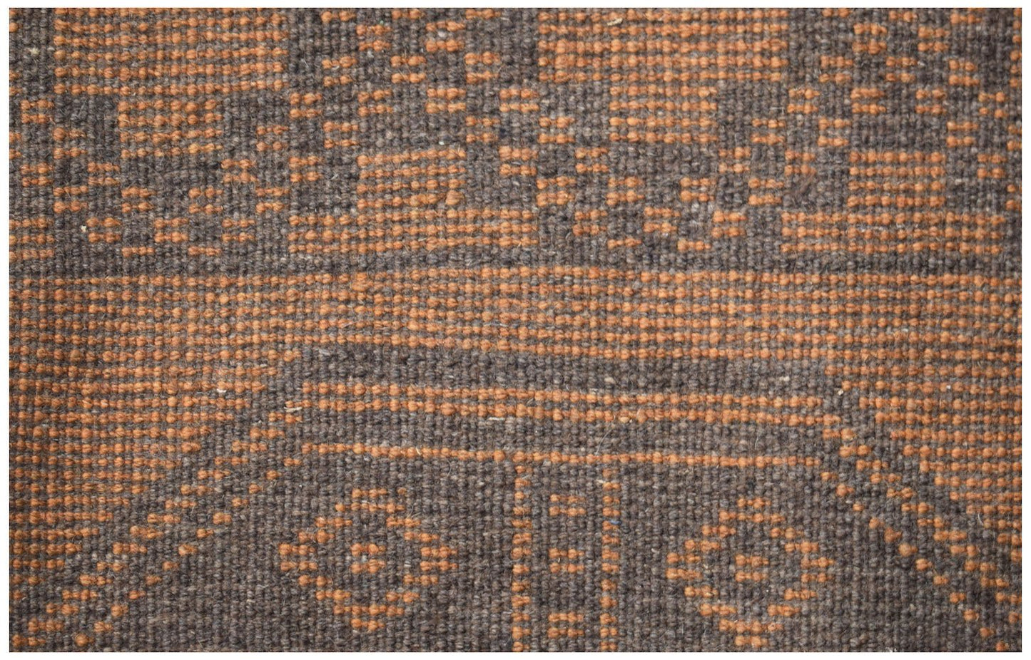 A handmade Afghan Baluch rug featuring a geometric pattern in shades of dark brown and orange.