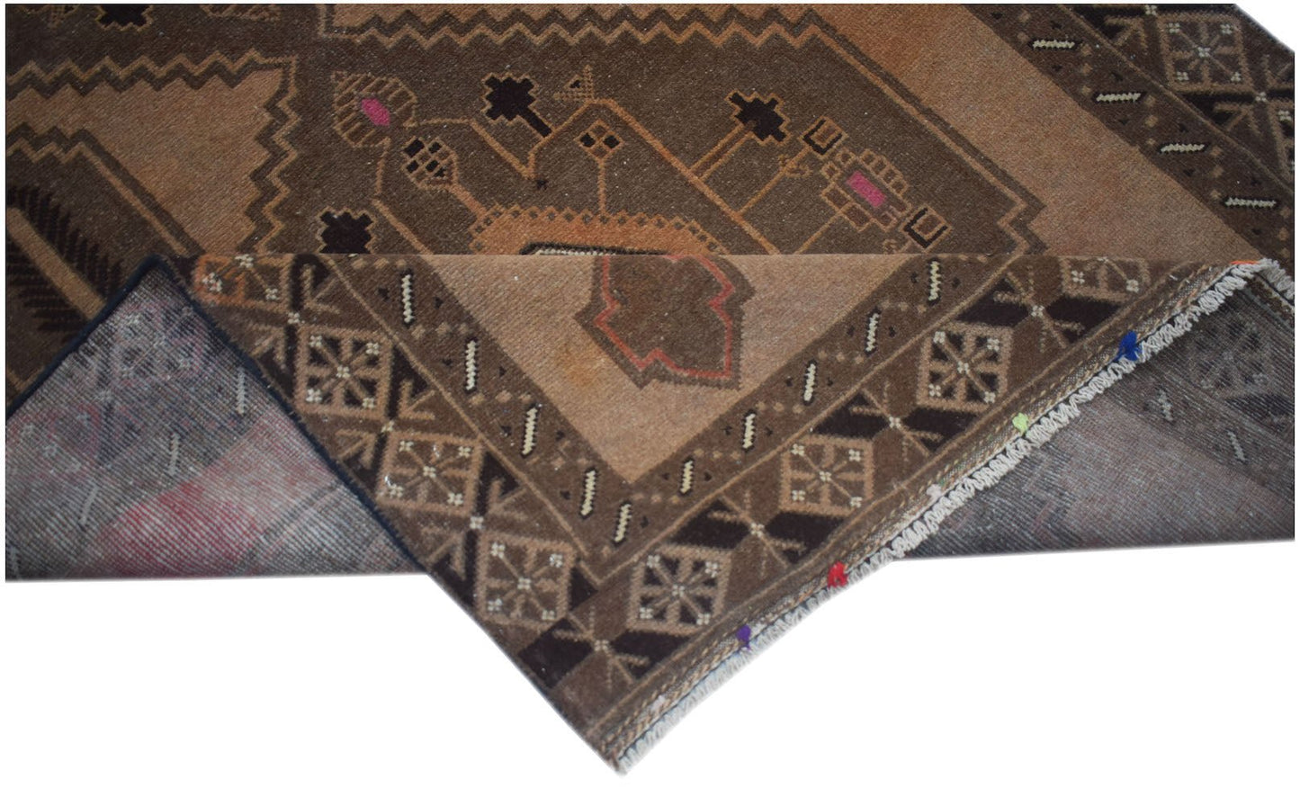 A handmade Afghan Baluch rug with a brown geometric pattern and a folded corner.