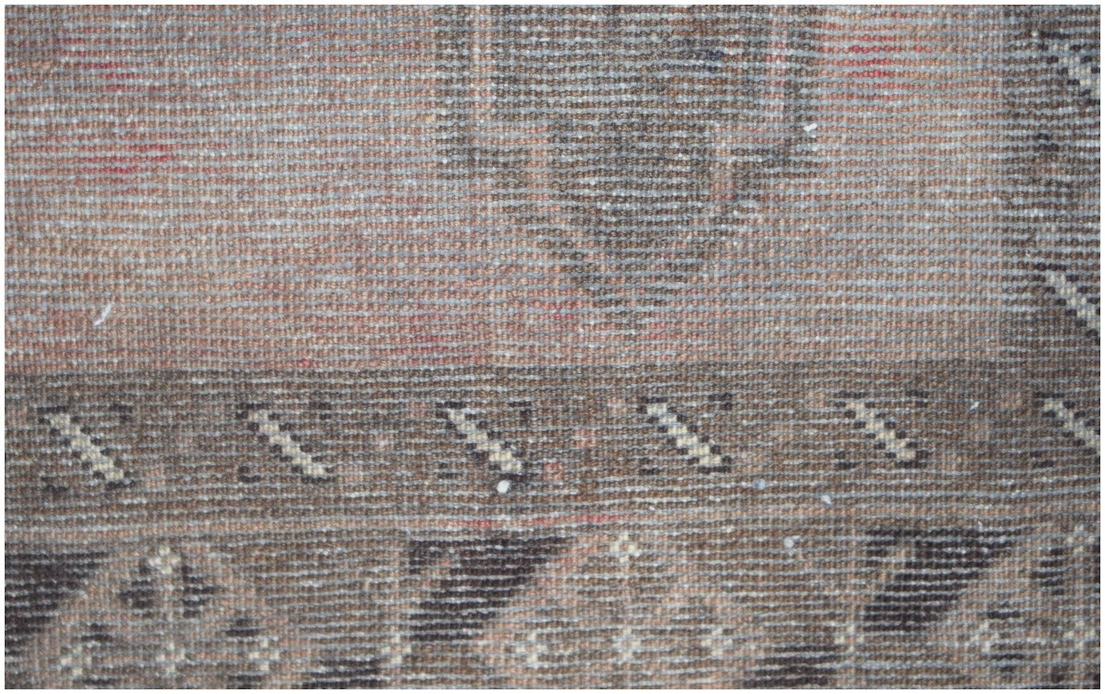A close-up view of a handmade Afghan Baluch rug featuring geometric patterns in earthy tones.