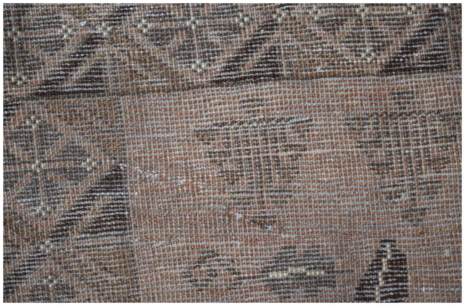 A close-up of a handmade Afghan Baluch rug featuring geometric patterns in brown and tan wool.