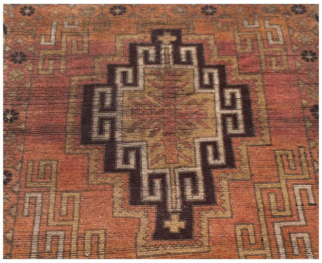 Handmade Afghan Baluch rug featuring a geometric diamond medallion in shades of orange and brown.