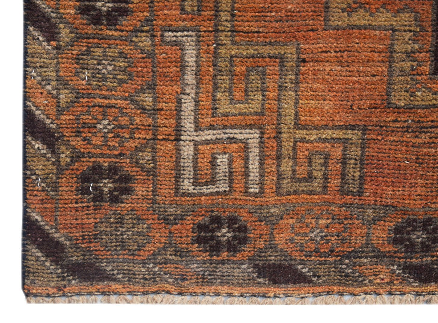 A close-up of an Afghan Baluch rug featuring geometric patterns in orange, brown, and cream wool.