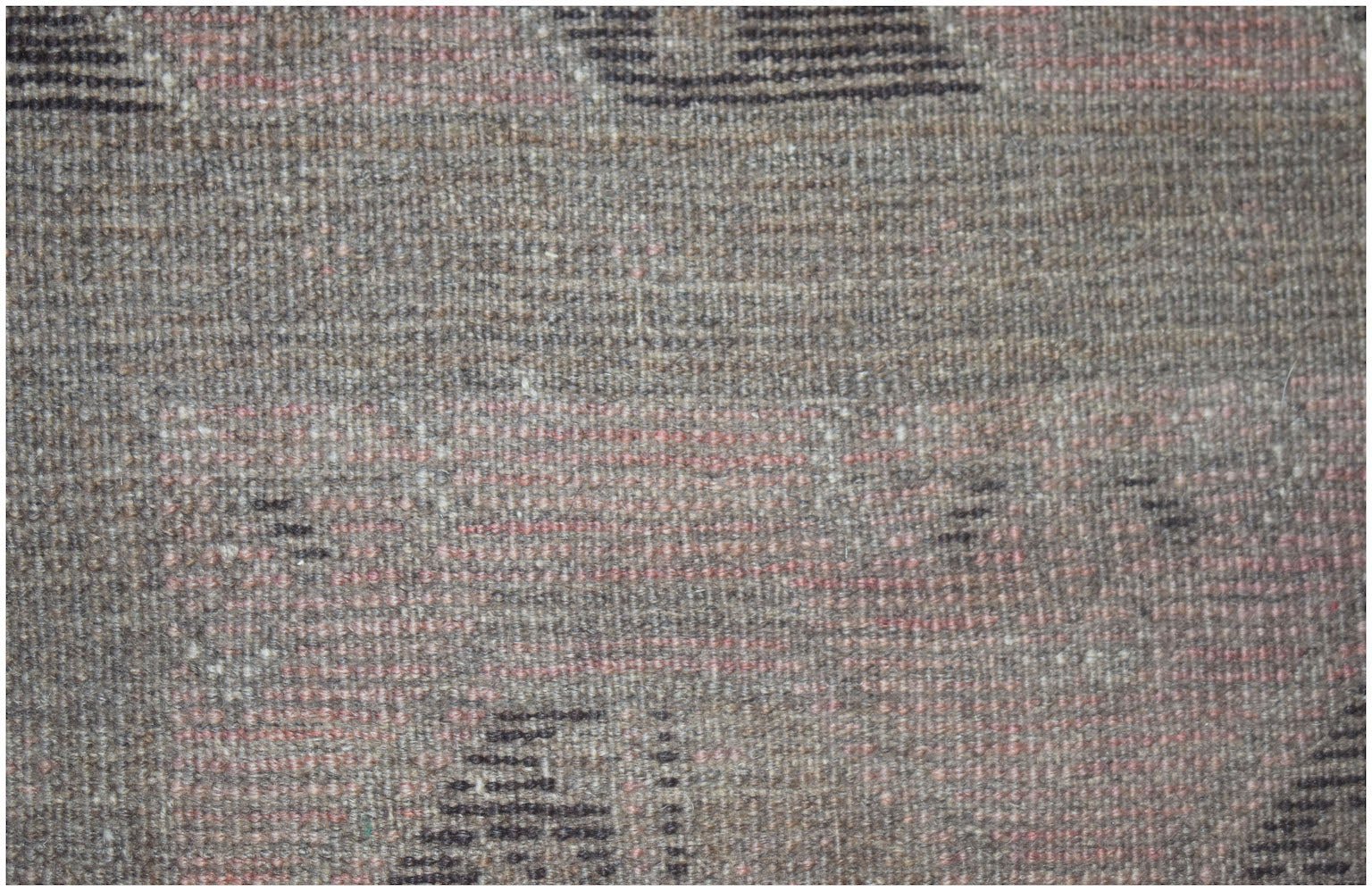 A close-up of a handmade Afghan Baluch rug featuring a textured wool weave in earthy tones.