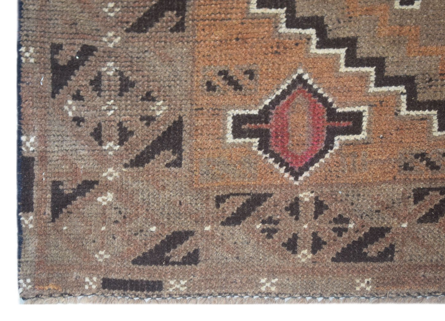 Handmade Afghan Baluch rug featuring geometric patterns in brown, orange, and red wool.