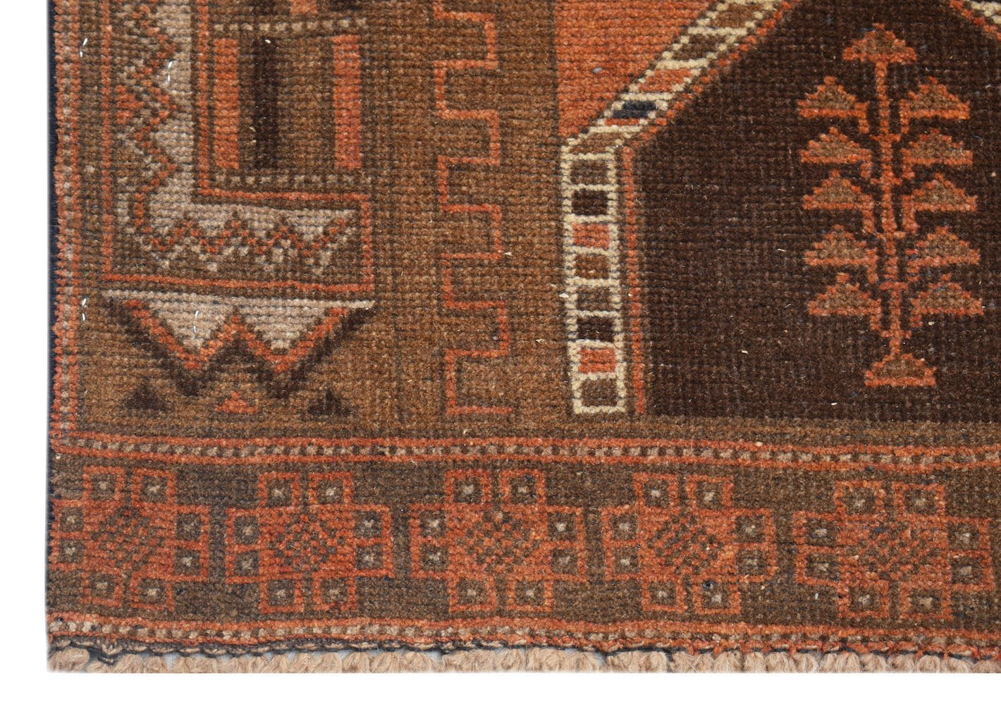 A close-up of an Afghan Baluch rug featuring geometric patterns and a tree motif in brown and orange.