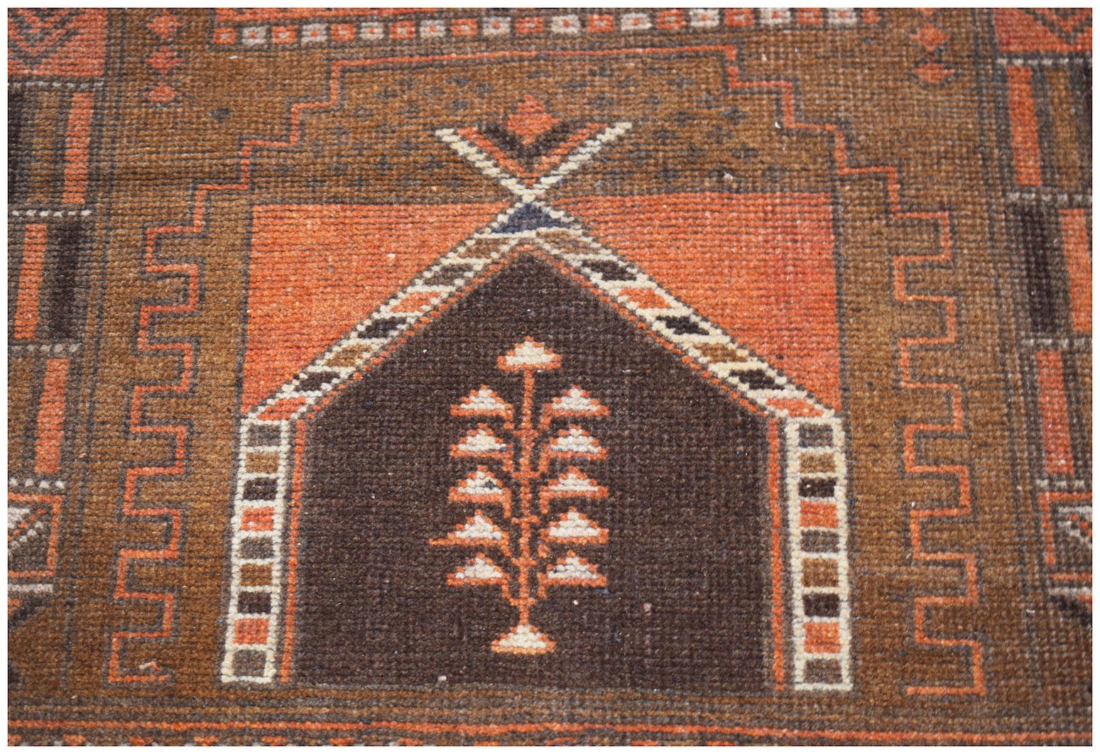 A handmade Afghan Baluch rug featuring a central tree motif within a geometric mihrab design.