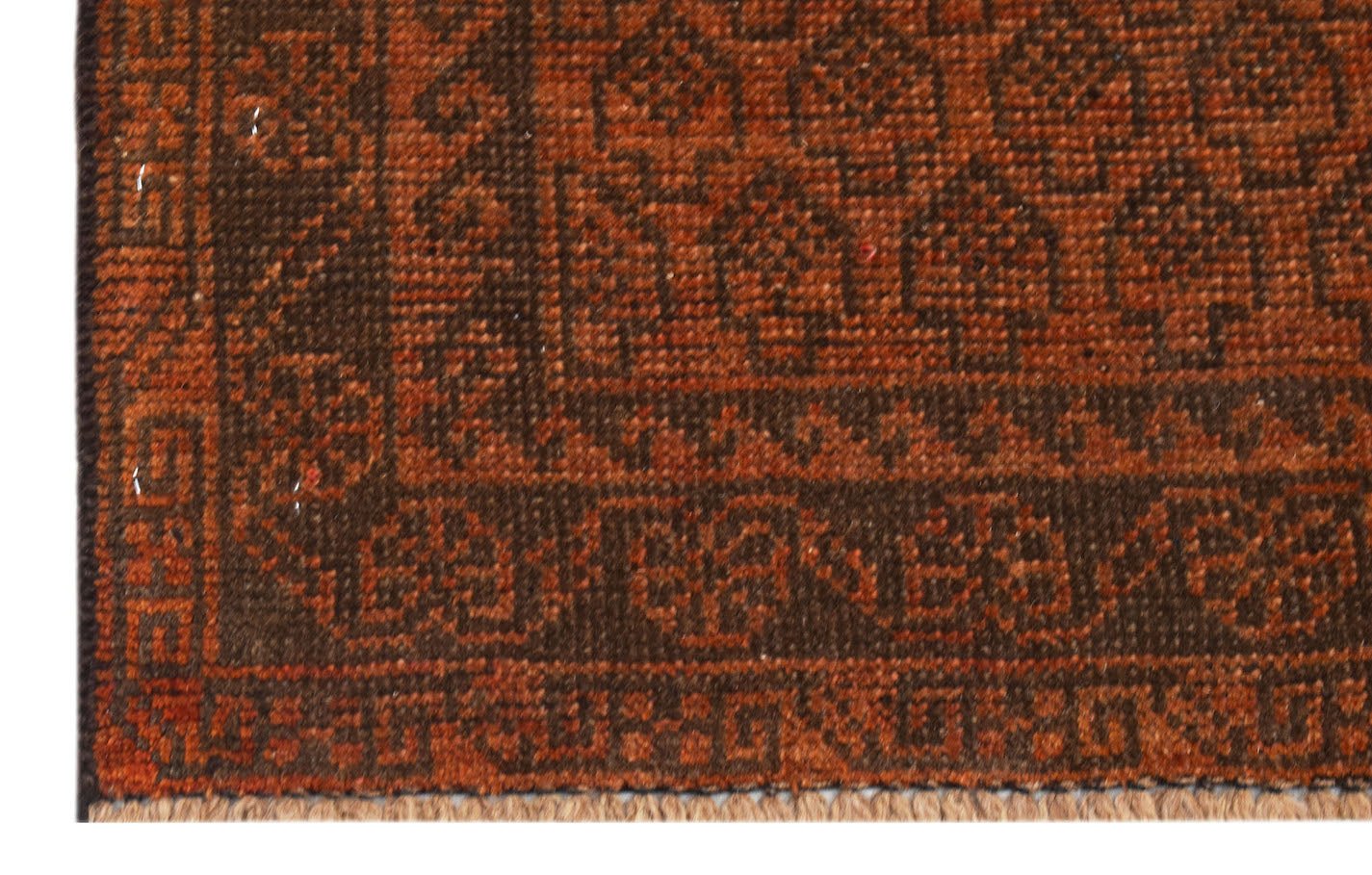 A close-up of an Afghan Baluch rug featuring geometric patterns in shades of brown and rust.