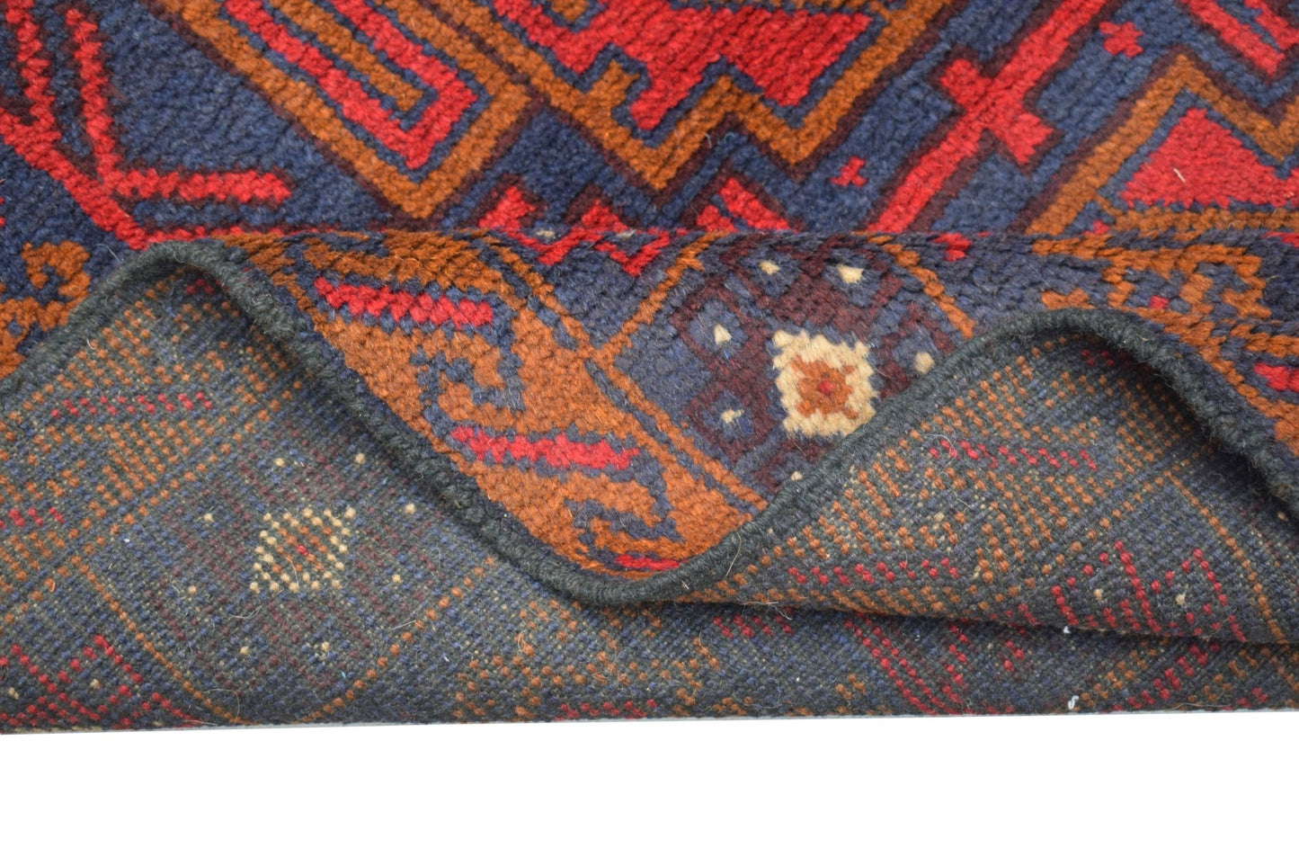 A handmade Afghan Baluch rug featuring geometric patterns in dark red, blue, and brown wool.