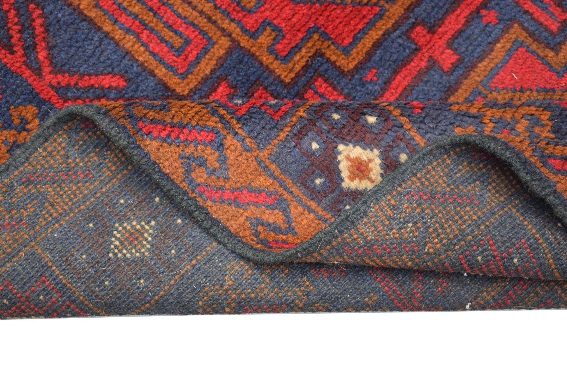 A handmade Afghan Baluch rug featuring geometric patterns in dark red, blue, and brown wool.
