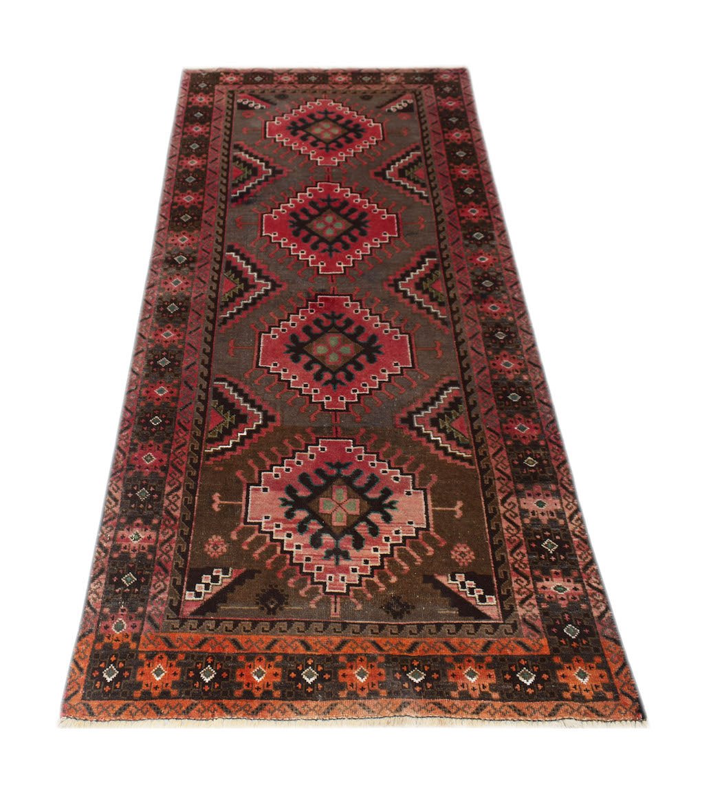 A handmade Afghan Baluch runner rug featuring geometric medallions in red and brown tones.