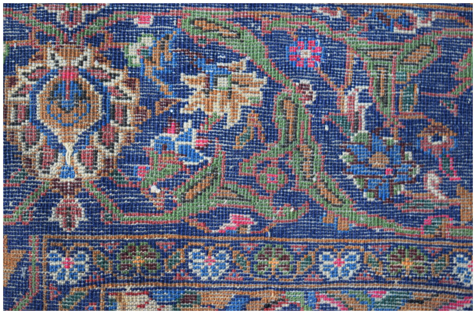 A close-up of a vintage Afghan Baluch rug featuring intricate floral patterns in blue and brown.