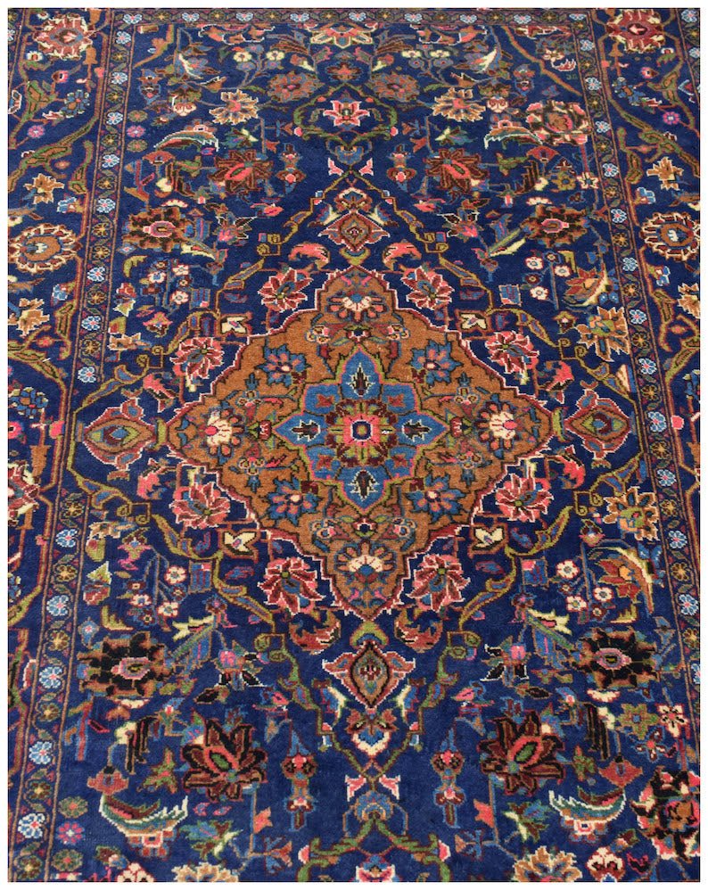A handmade vintage Afghan Baluch rug featuring a central medallion on a deep blue floral field.