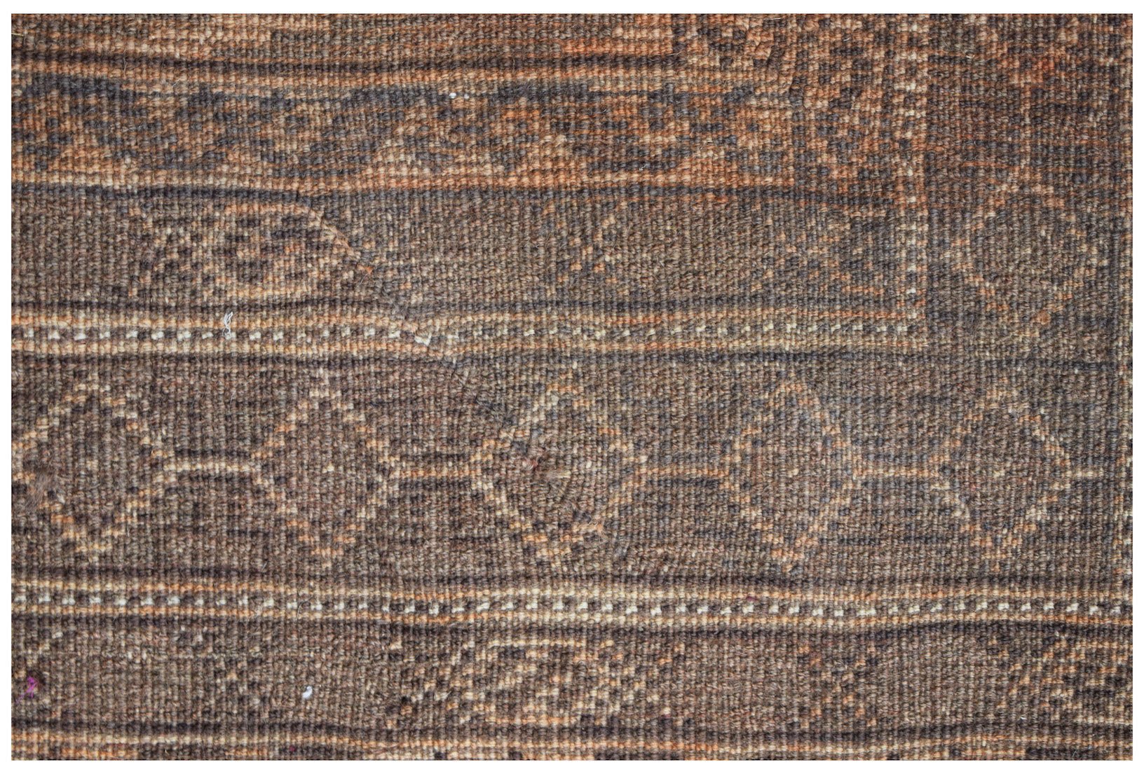 A handmade Afghan Baluch wool rug featuring a geometric diamond pattern in shades of brown.