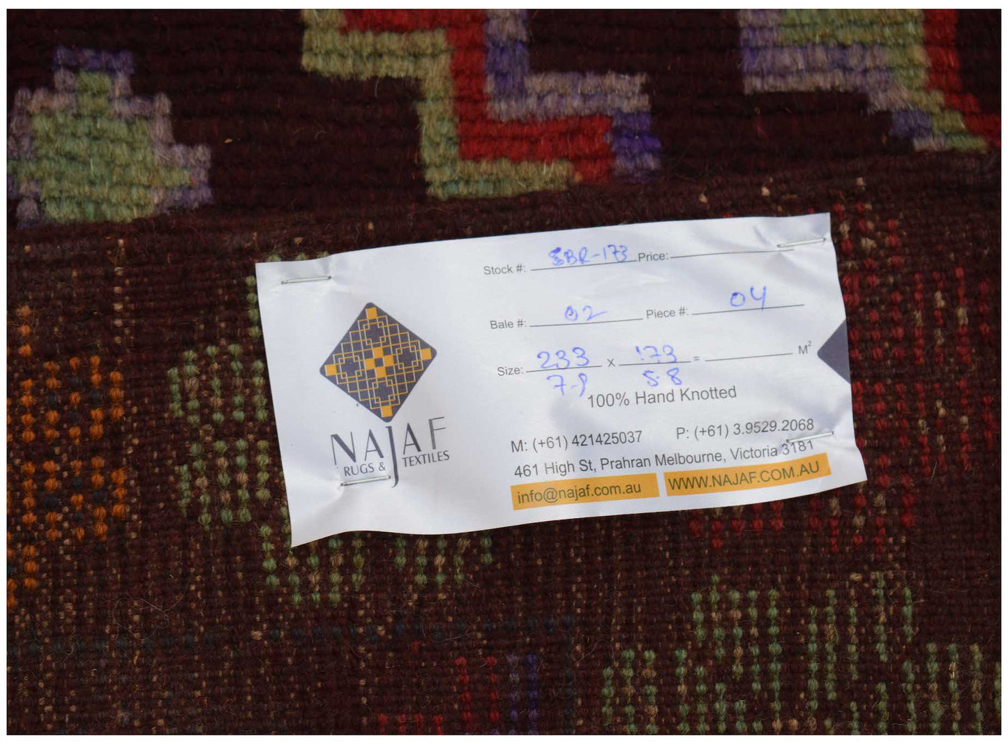 A handmade Afghan Pashm rug featuring a dark red, brown, and blue tribal geometric pattern.
