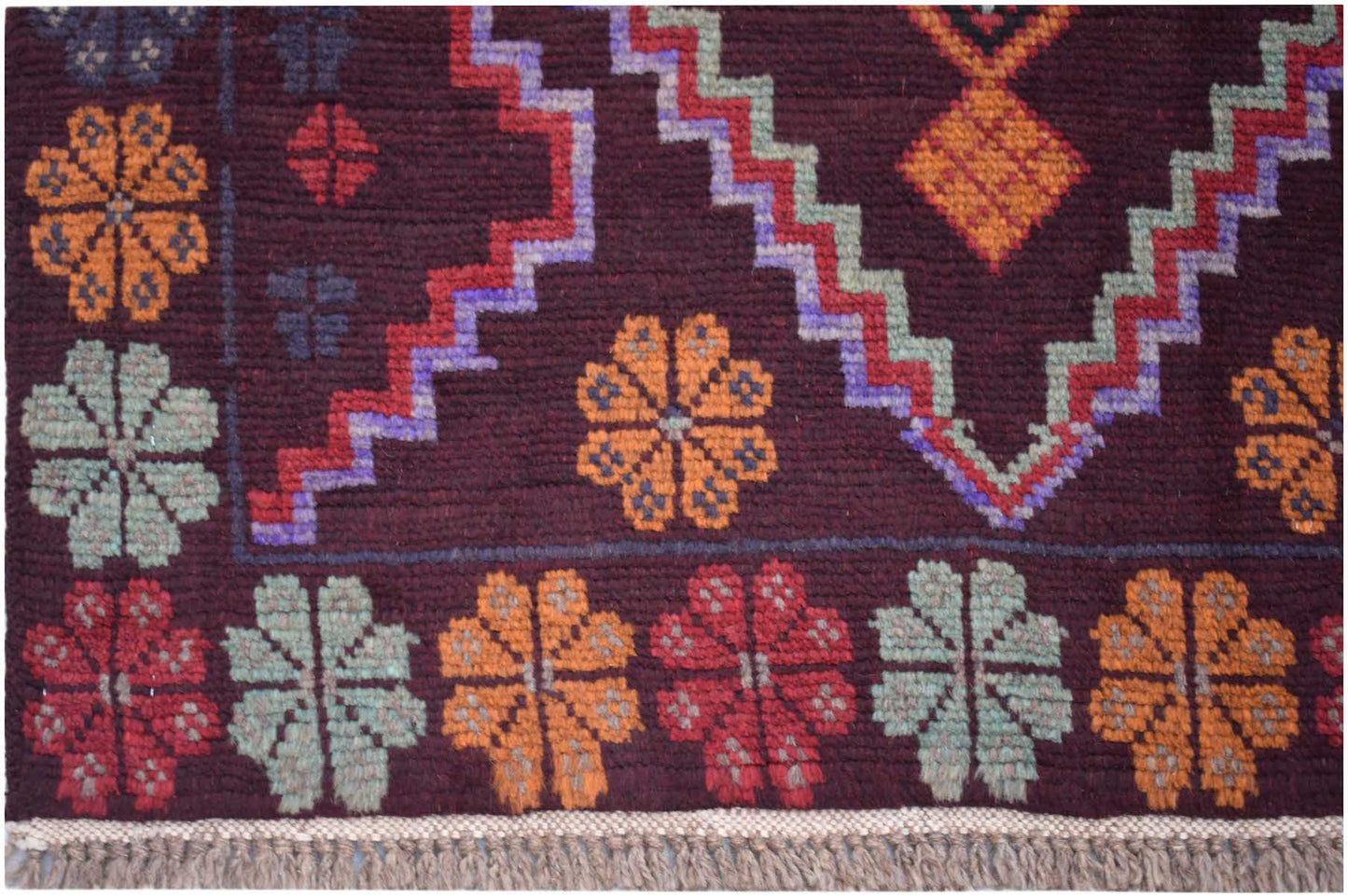 Handmade Afghan Pashm rug featuring geometric floral patterns in orange, red, and blue on dark wool.