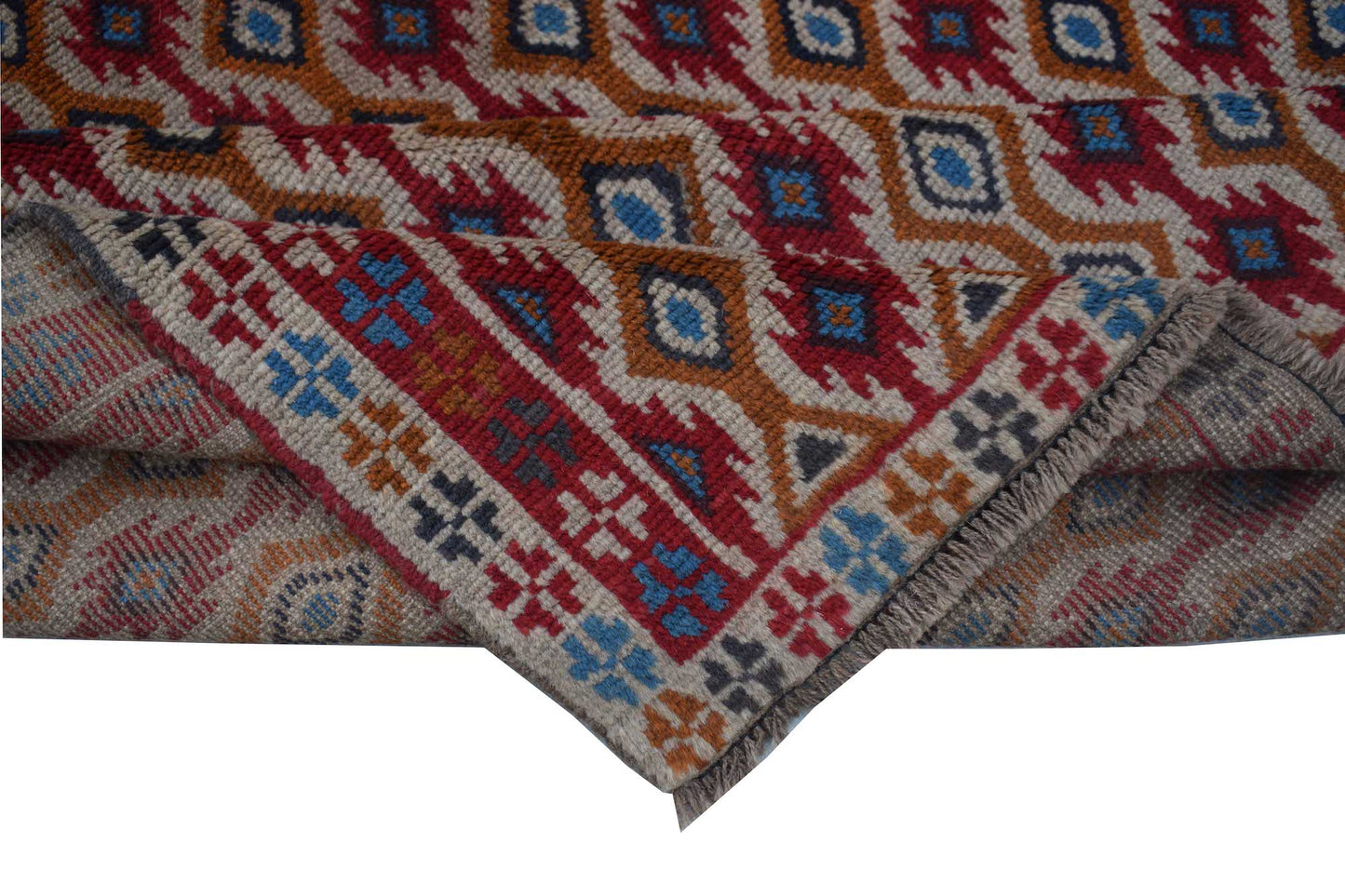 A handmade Afghan Pashm rug featuring a geometric tribal pattern in red, blue, and ivory wool.