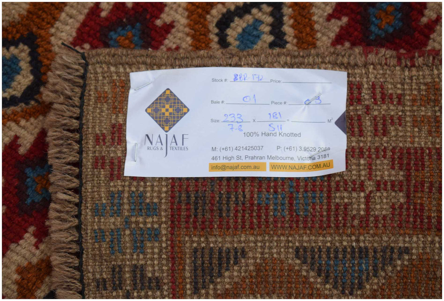 A handmade Afghan Pashm rug featuring a tribal pattern in shades of red, brown, and blue.