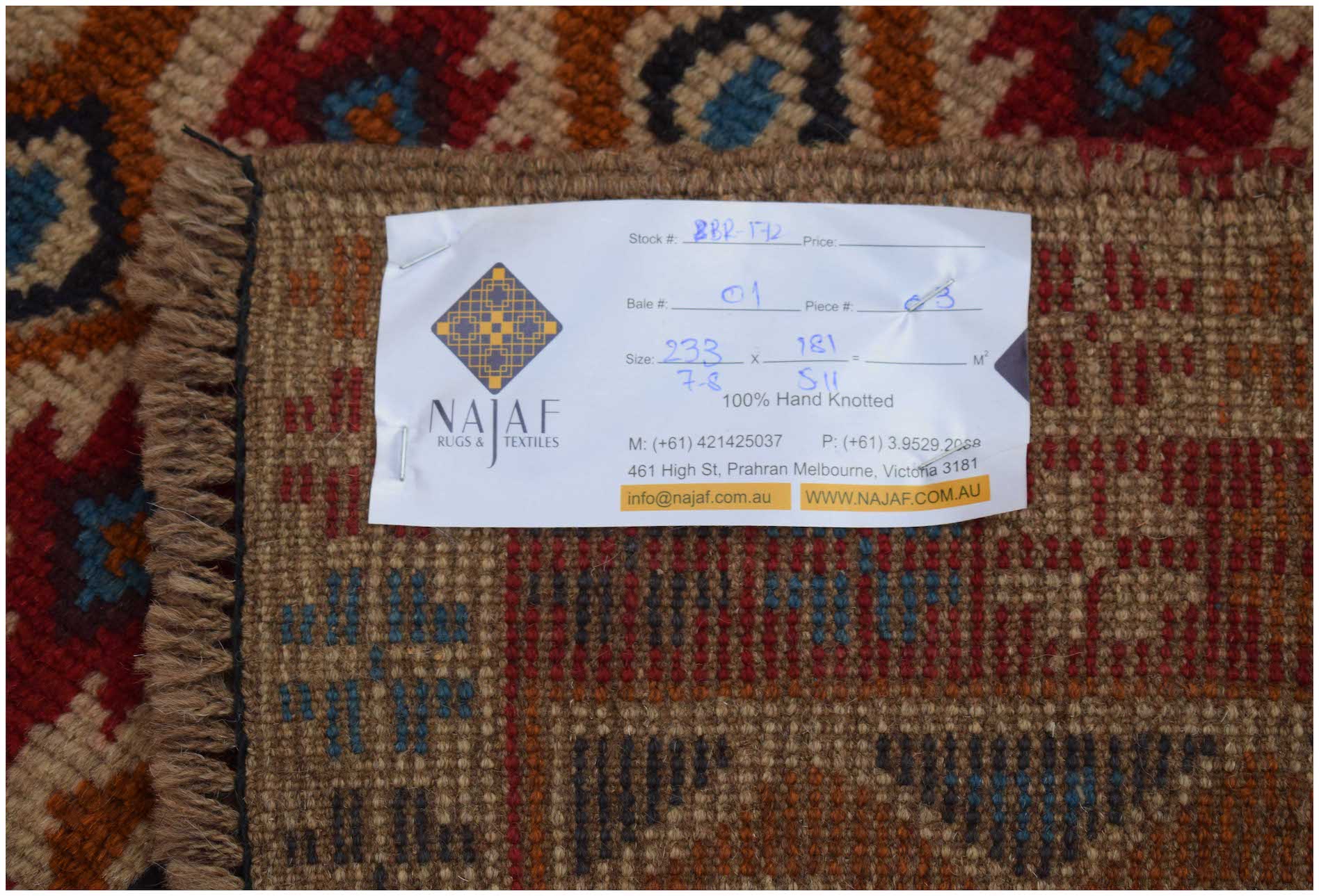 A handmade Afghan Pashm rug featuring a tribal pattern in shades of red, brown, and blue.