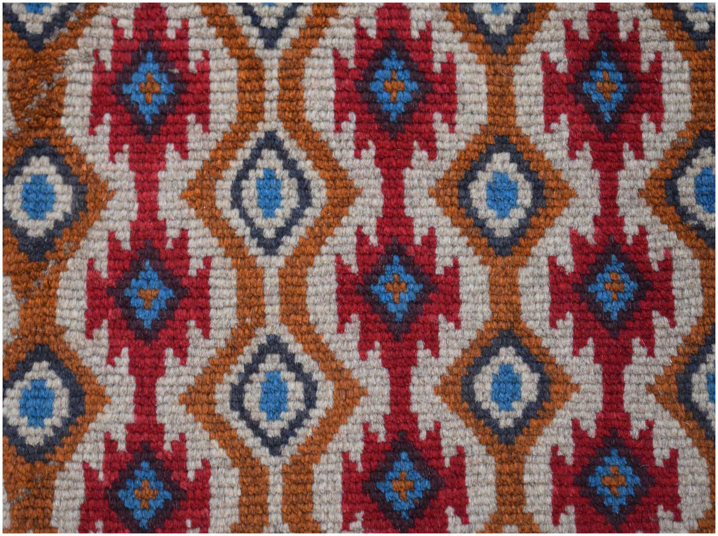 Handmade Afghan Pashm rug featuring a geometric pattern in red, blue, brown, and ivory wool.