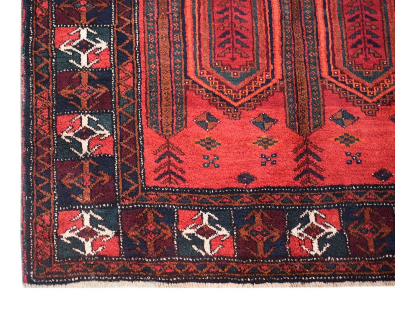 A vintage handmade Afghan Baluch wool rug featuring traditional geometric patterns in red and blue.