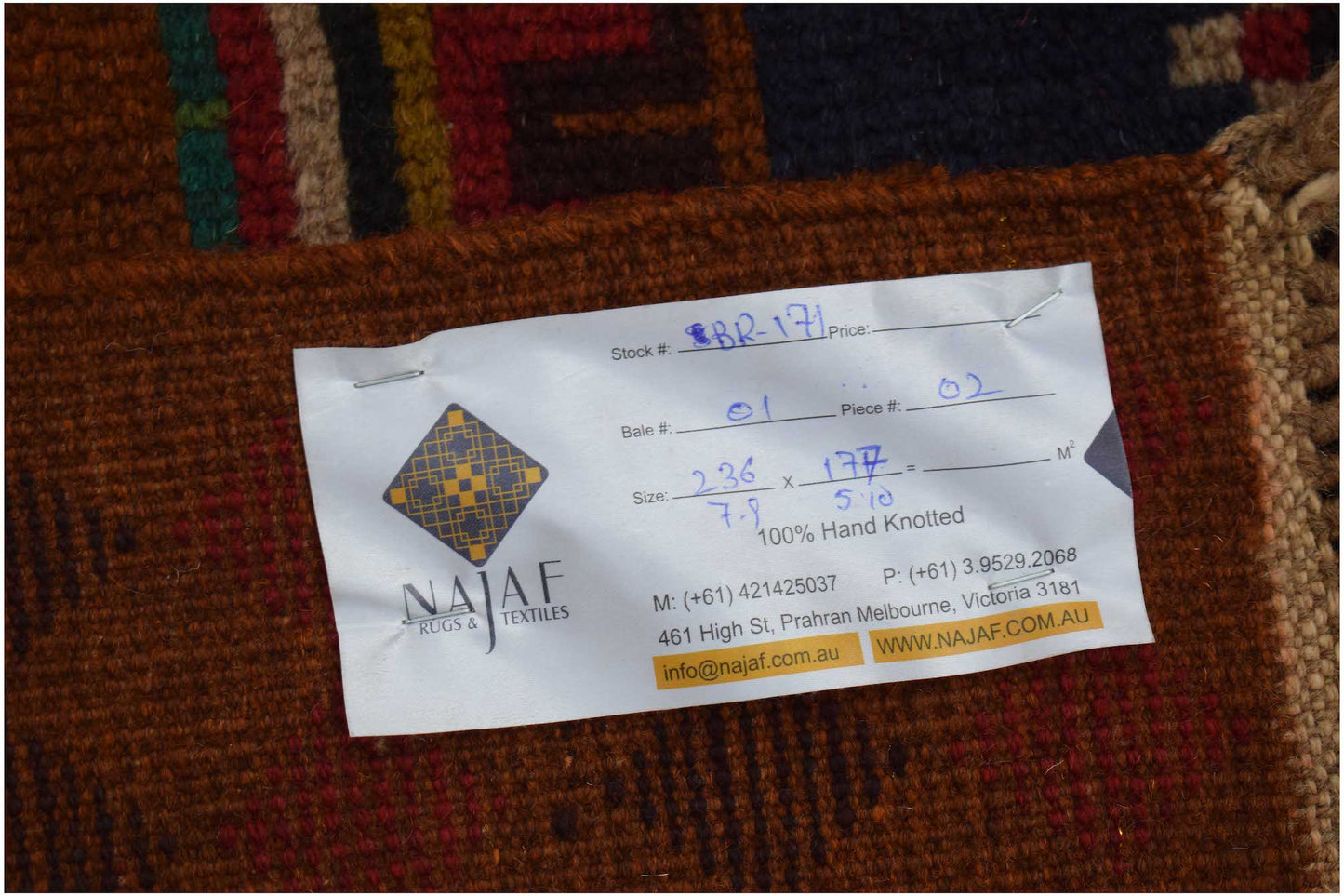 A close-up view of the back of a handmade Afghan Pashm rug featuring a product information tag.