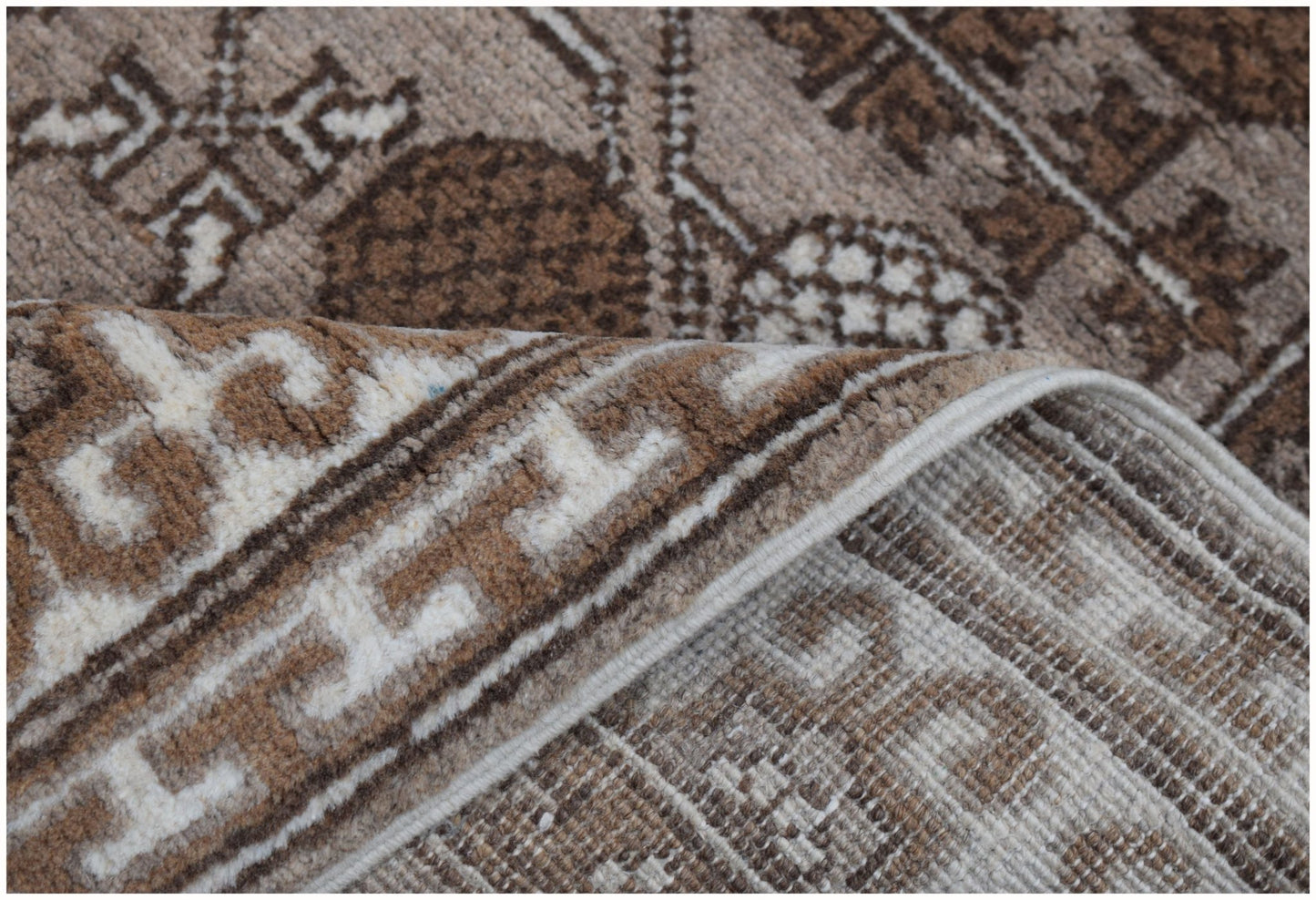 A close-up of a handmade Afghan Chobi runner featuring a brown and cream geometric pattern.