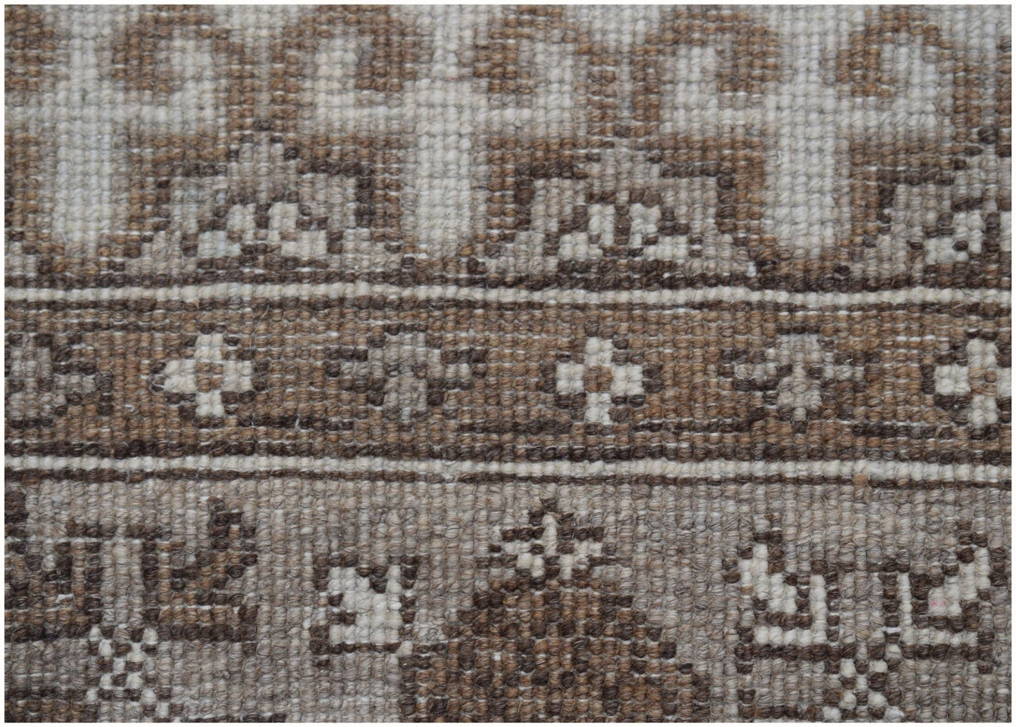 A close-up of a handmade Afghan Chobi runner featuring intricate geometric patterns in natural wool.