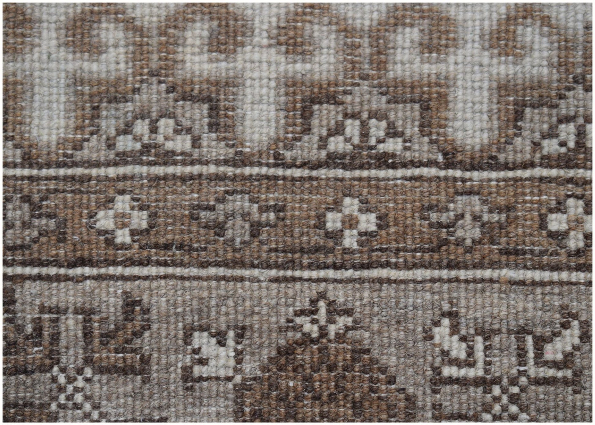 A close-up of a handmade Afghan Chobi runner featuring intricate geometric patterns in natural wool.