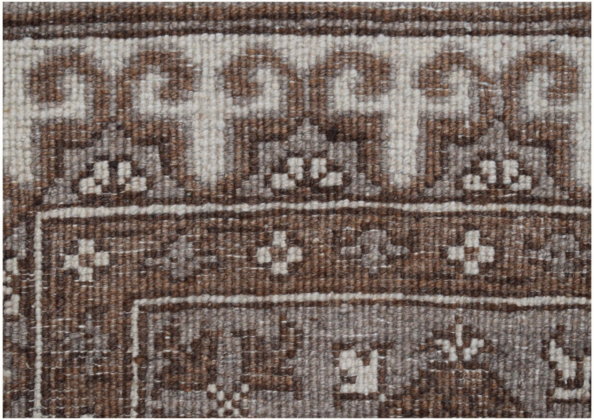 A close-up of a handmade Afghan Chobi runner featuring intricate brown and cream geometric patterns.