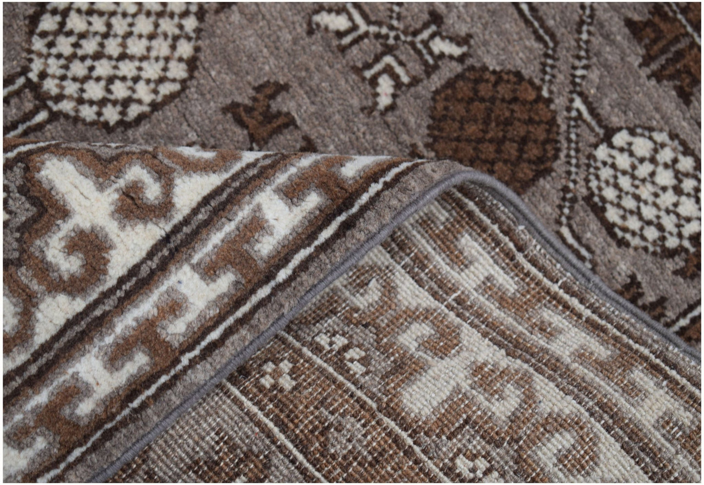 A close-up view of a handmade Afghan Chobi runner featuring a brown and cream geometric pattern.