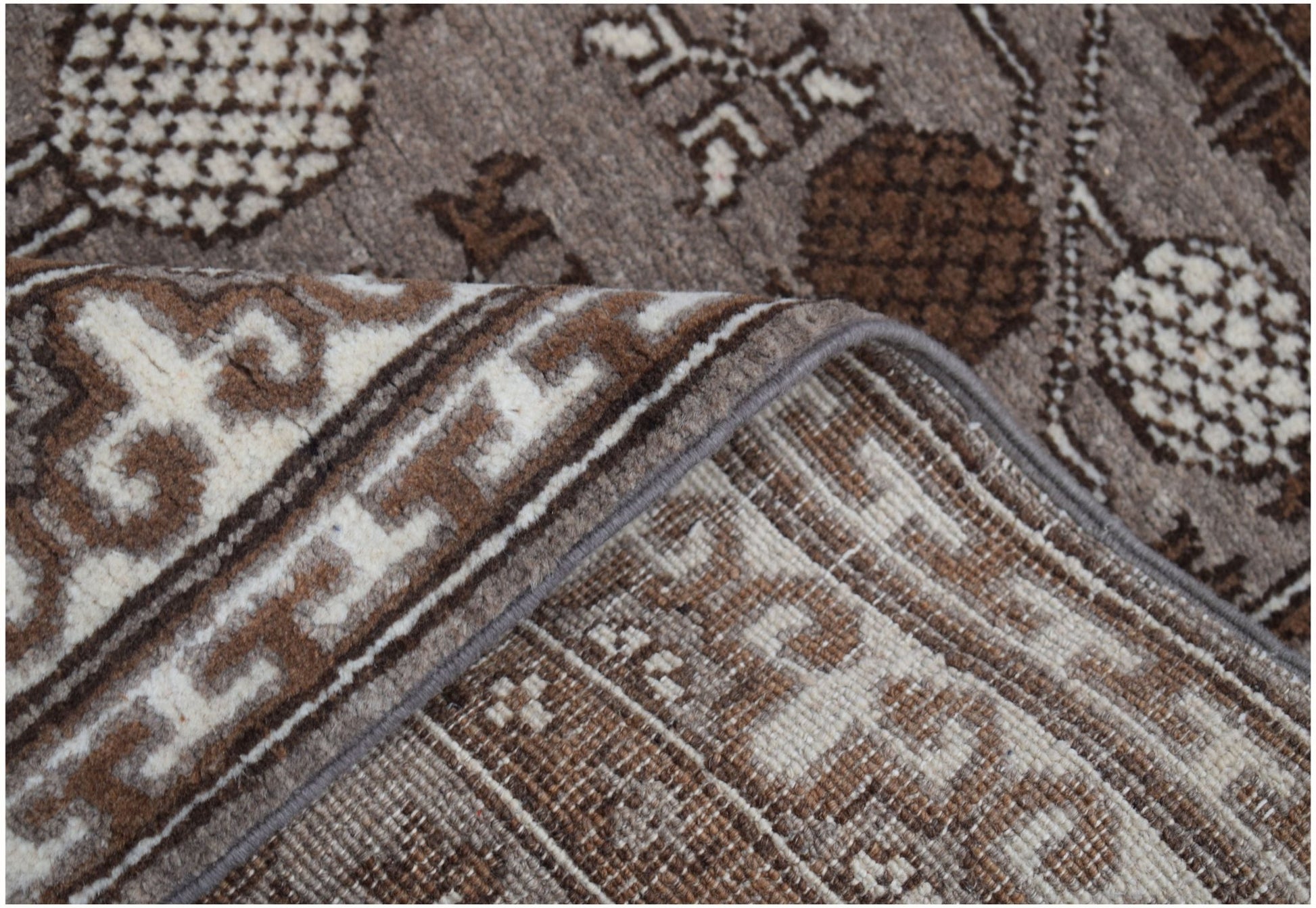 A close-up view of a handmade Afghan Chobi runner featuring a brown and cream geometric pattern.