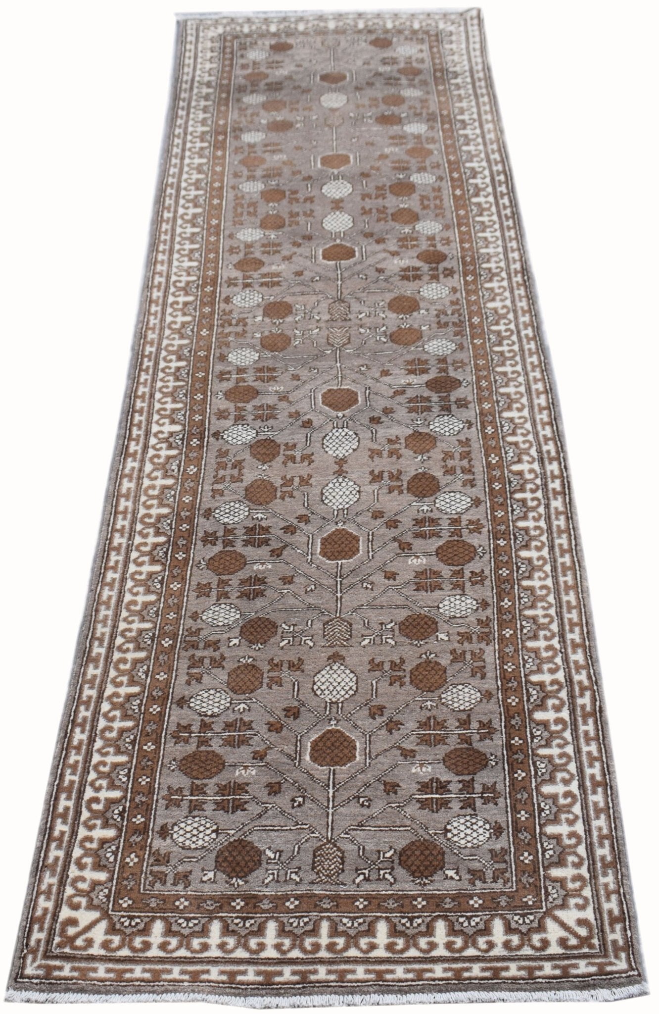 A handmade Afghan Chobi runner rug featuring a repeating geometric floral pattern in brown and cream.
