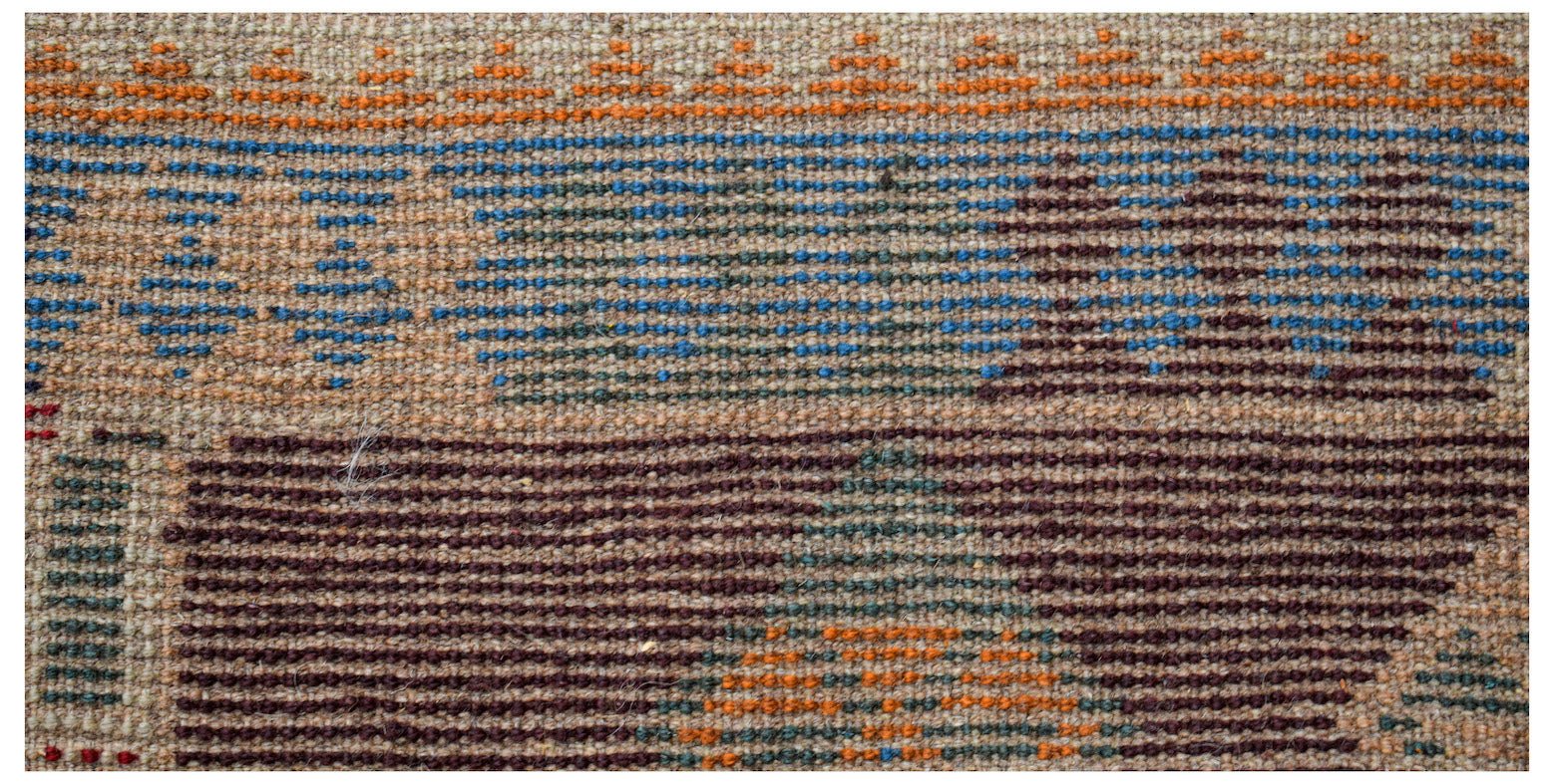A handmade Afghan Pashm rug featuring a geometric pattern in shades of blue, brown, and orange.