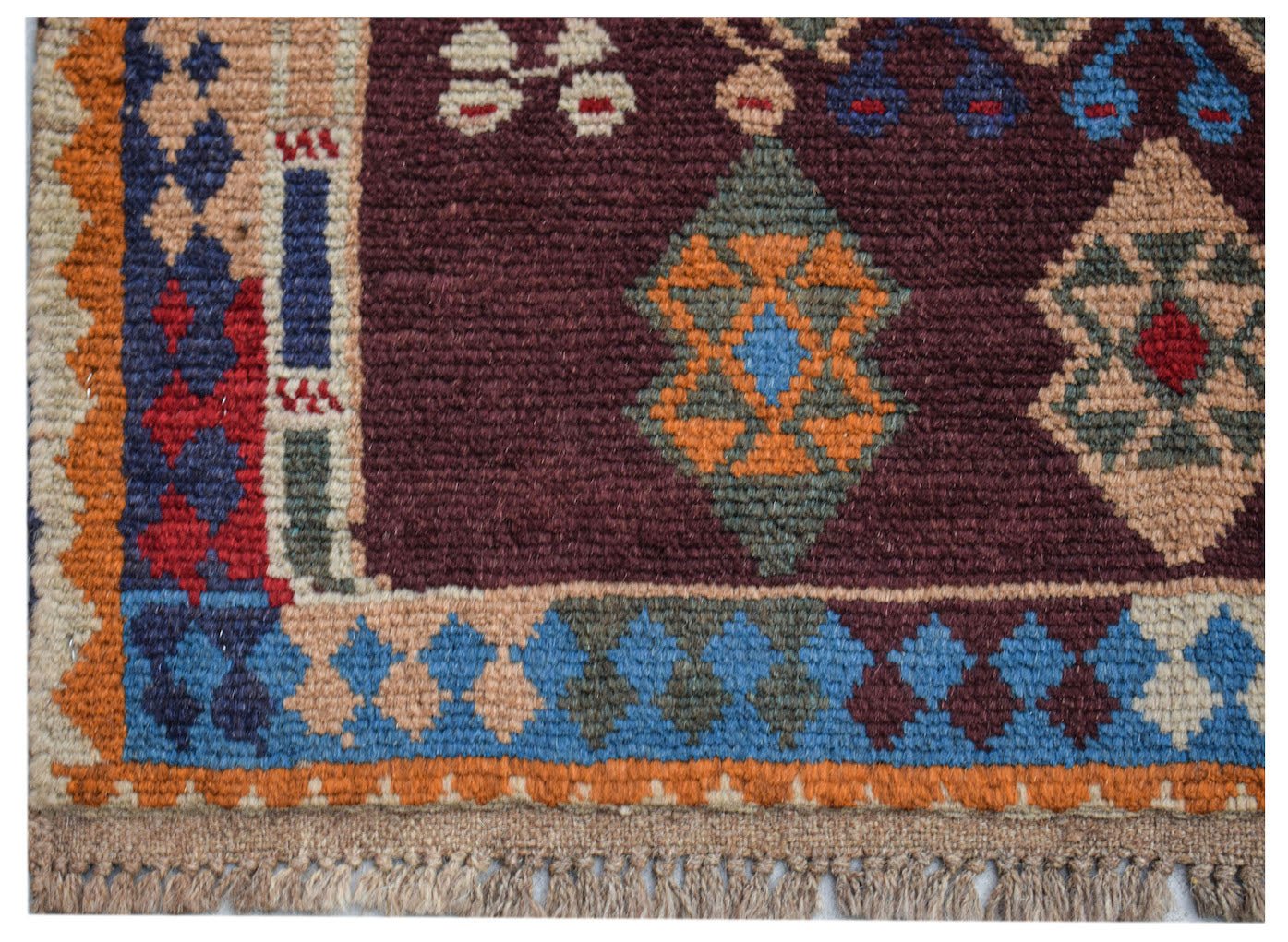 Handmade Afghan Pashm rug featuring a dark red field with geometric diamond patterns and fringe.