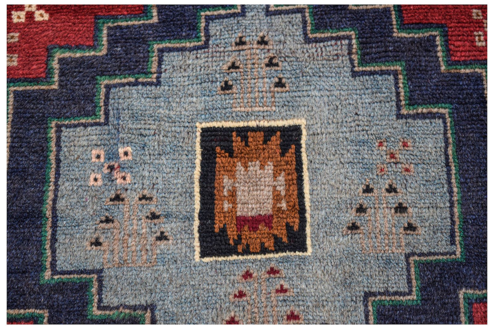 Handmade Afghan Pashm rug featuring a central geometric motif in blue, red, and brown wool.