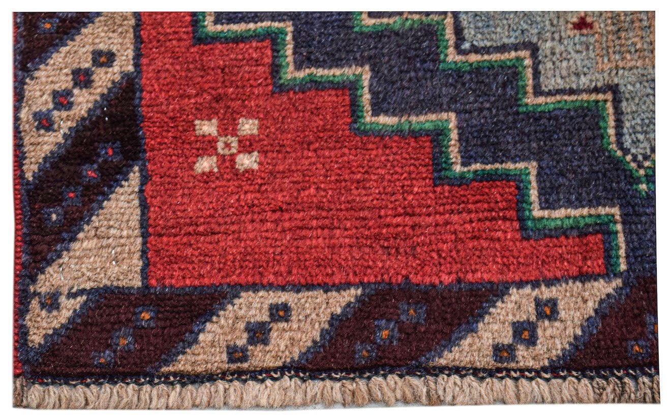 A handmade Afghan Pashm rug featuring a geometric pattern in deep red, blue, and ivory wool.